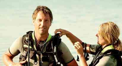 To personer i dykkerutstyr står i grunt vann. (AI-generert tekst)