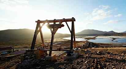 En trestruktur ved saltbassenger med fjell i bakgrunnen. (AI-generert tekst)