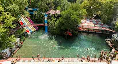 Vannpark med flere vannsklier og badeområde omgitt av grøntområder. (AI-generert tekst)