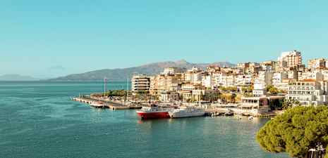 Utsikt over en by ved sjøen med småbåthavn og bygninger langs kysten. (AI-generert tekst)