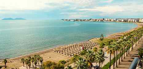Strand med parasoller og havet i bakgrunnen. (AI-generert tekst)