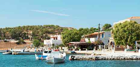 Havnemiljø med småbåter, hus og trær ved kysten. (AI-generert tekst)