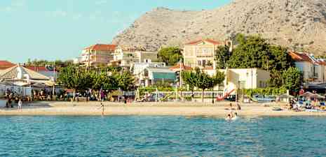 Utsikt over en strand med bygninger og fjell i bakgrunnen. (AI-generert tekst)