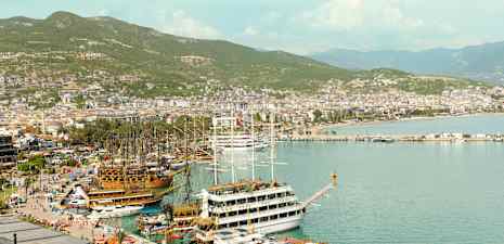 Havn med båter og kystlinjen til byen Alanya i bakgrunnen. (AI-generert tekst)