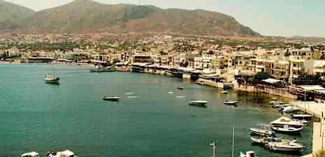 En kystby med båter i havnen og bygninger langs strandlinjen. (AI-generert tekst)