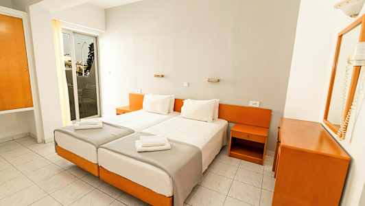 To enkeltsenger med hvite sengetepper i et hotellrom med hvit og treinnredning. (AI-generert tekst)