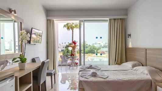 Hotellrom med to enkeltsenger, skrivebord og balkong med sitteplasser. (AI-generert tekst)