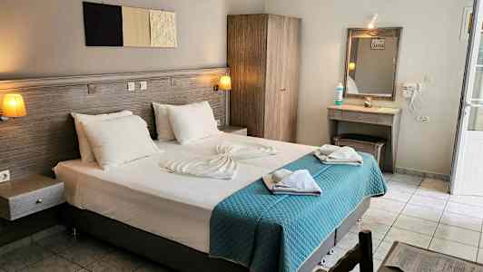 Hotellrom med en dobbeltseng, garderobe, sminkbord og lyse tekstiler. (AI-generert tekst)