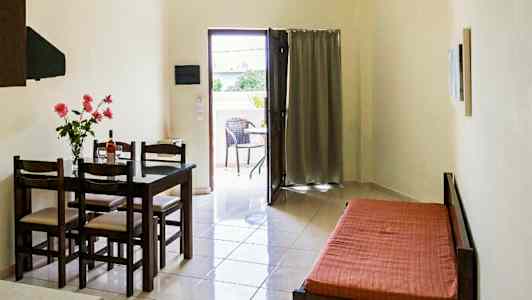 Et rom med et spisebord og stoler, en sovesofa, og en åpning som fører til en balkong. (AI-generert tekst)