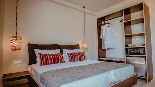 Soverom med dobbeltseng, røde dekorative puter og åpen garderobe. (AI-generert tekst)