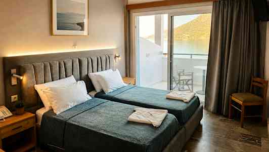 Hotellrom med to enkeltsenger, nattbord og bilde på veggen. Balkong med utsikt over vann og fjell. (AI-generert tekst)