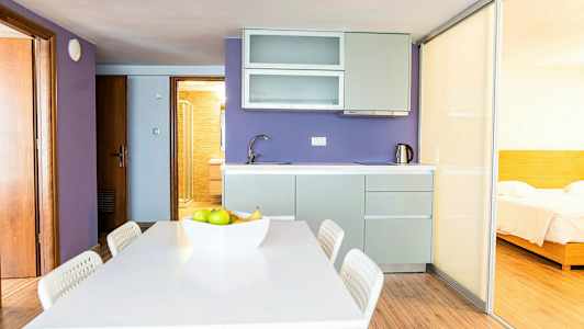 Et kjøkken med lilla vegger, en spiseplass og en skyvedør som fører til et soverom. (AI-generert tekst)