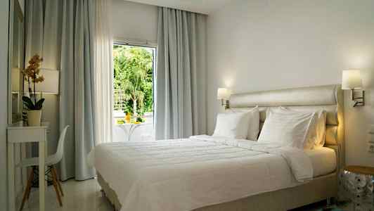 Lyst og moderne innredet hotellrom med en stor seng og vindu med utsikt. (AI-generert tekst)