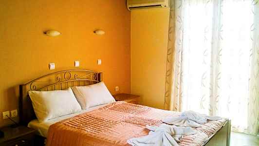 Et soverom med en dobbeltseng, oransje sengetøy og to håndklær dekorert på sengen. (AI-generert tekst)