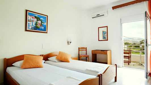 Hotellrom med to enkeltsenger, et skrivebord med stol og balkong med utsikt. (AI-generert tekst)