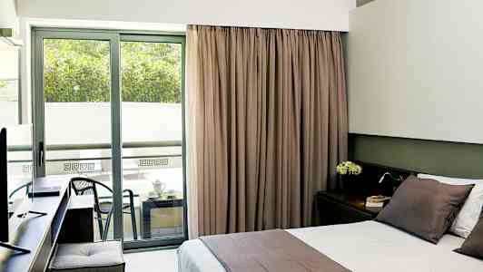 Hotellrom med dobbeltseng og balkong med sittemøbler. (AI-generert tekst)