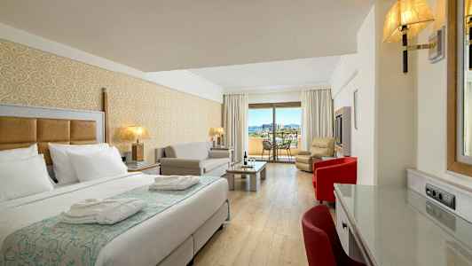 Et hotellrom med en seng, sittegruppe og en balkong med utsikt. (AI-generert tekst)