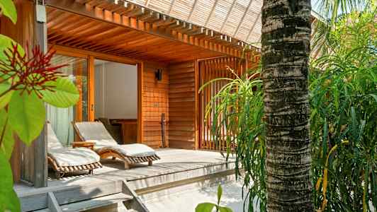 Treterrasse med solsenger og omkringliggende grøntområder ved en trebygning. (AI-generert tekst)