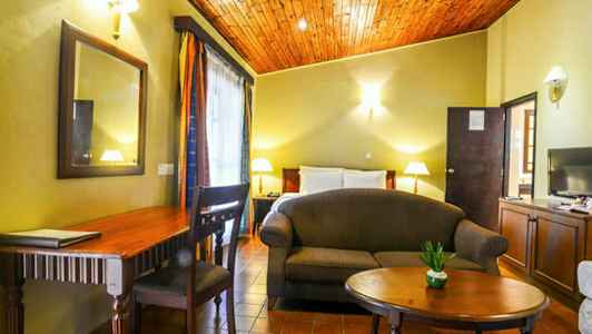 Et rom med seng, sofa, bord, skrivebord og dekorasjoner. (AI-generert tekst)