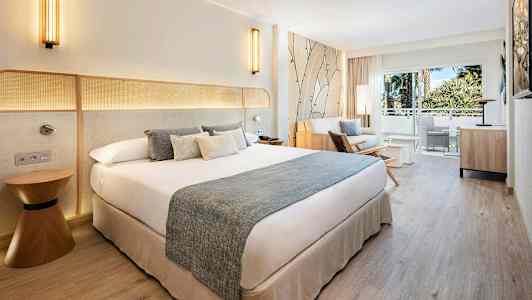 Hotellrom med dobbeltseng, sofagruppe og balkong med utsikt. (AI-generert tekst)