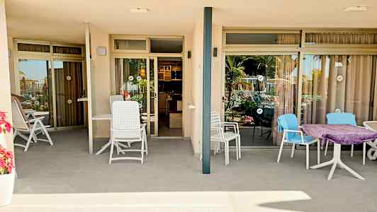 Bilde av to terrasser med sittemøbler foran glassdører som leder inn til leiligheter. (AI-generert tekst)