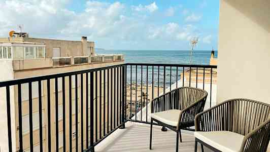 En balkong med to stoler og utsikt over havet. (AI-generert tekst)