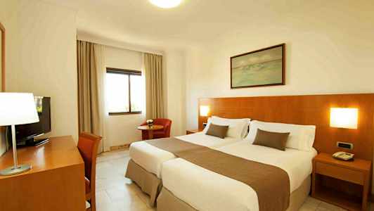 Et hotellrom med to enkeltsenger og trepanel på veggen. (AI-generert tekst)