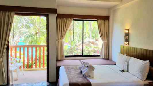 Et hotellrom med åpen dør til en balkong og en seng med dekorasjoner. (AI-generert tekst)