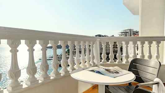 En balkong med utsikt over havet, et rundt bord og en svart stol. (AI-generert tekst)