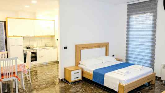 Et soverom med en dobbeltseng, bord med stoler og en liten kjøkkenkrok. (AI-generert tekst)