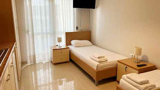 Et rom med to enkeltsenger, sidebord og en veggmontert TV. (AI-generert tekst)