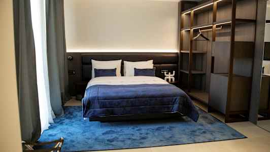 Et komfortabelt hotellrom med en dobbeltseng, blå sengetøy og en elegant innredning. (AI-generert tekst)