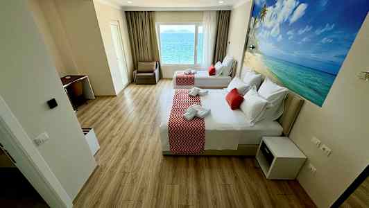 Et hotellrom med to senger, skrivebord og havutsikt fra vinduet. (AI-generert tekst)