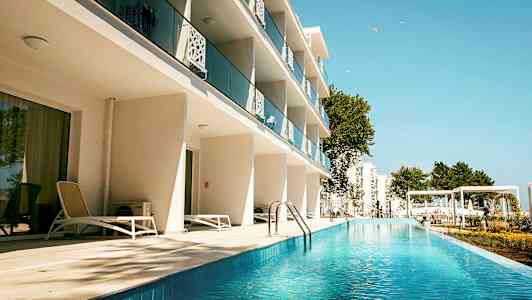 Hotellbygning med balkonger og bassengområde. (AI-generert tekst)