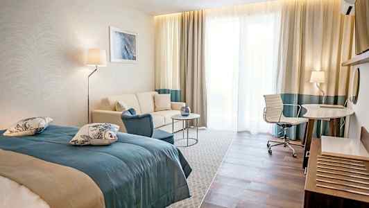 Et hotellrom med en seng, sofa, bord og skrivebord med stol. (AI-generert tekst)