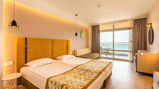 Bilde av et hotellrom med en dobbeltseng og utsikt mot havet fra et vindu. (AI-generert tekst)