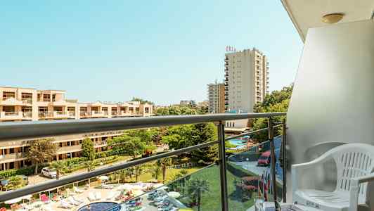 Leilighetsbalkong med utsikt over bassengområdet og hotellbygninger. (AI-generert tekst)