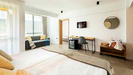 Moderne hotellrom med dobbeltseng, sofa og skrivebord. (AI-generert tekst)