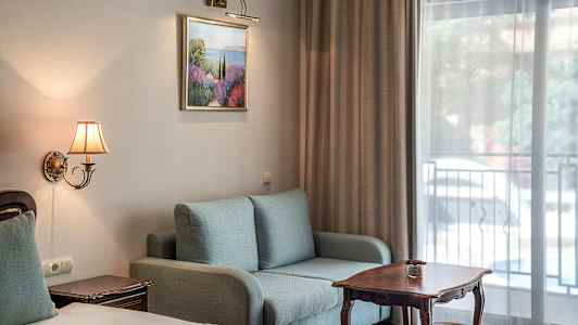 Interiør av et hotellrom med sofa, bord og seng. (AI-generert tekst)