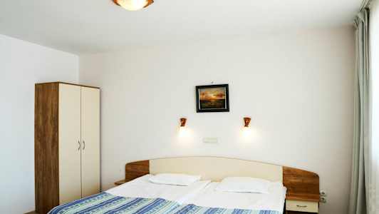 Et hotellrom med en dobbeltseng, nattbord og garderobe. (AI-generert tekst)