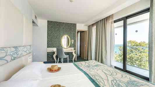 Hotellrom med lyse møbler og store vinduer med utsikt over havet. (AI-generert tekst)