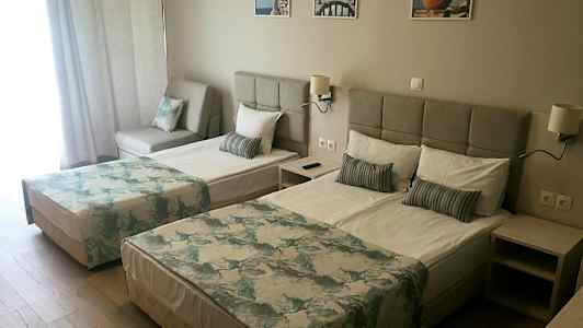 Dobbeltrom med to senger, en sofa og lys innredning. (AI-generert tekst)