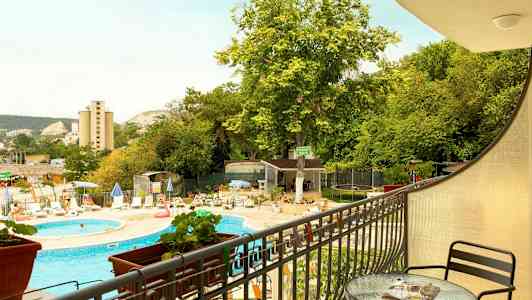 Utsikt fra en veranda mot et utendørsbasseng, solsenger og vegetasjon. (AI-generert tekst)