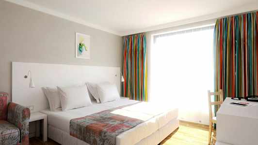 Et hotellrom med en seng, et skrivebord og fargerike gardiner. (AI-generert tekst)