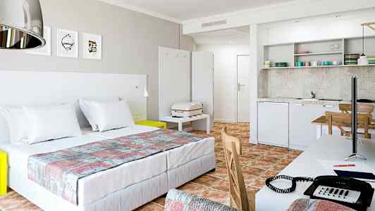 Moderne hotellrom med dobbeltseng, kjøkken og arbeidsbord. (AI-generert tekst)