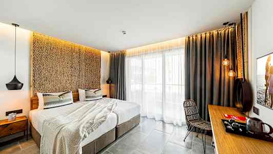 Moderne innredet hotellrom med dobbeltseng, sittegruppe og balkong. (AI-generert tekst)