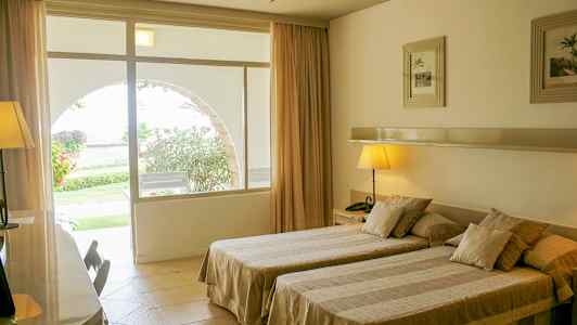 Et hotellrom med to enkeltsenger, vindu som vender mot en hage. (AI-generert tekst)