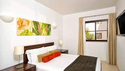 Et soverom med en dobbeltseng og veggdekorasjoner som viser blomsterbilder. (AI-generert tekst)