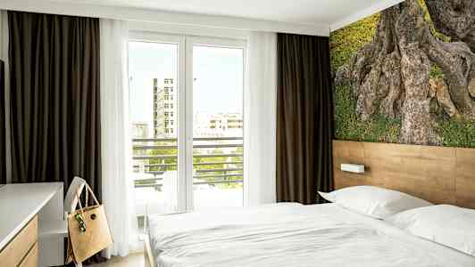 Et hotellrom med en seng, en skrivebordstol og et naturmotiv på veggen. (AI-generert tekst)