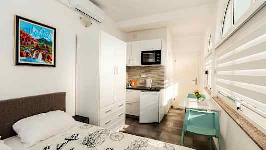 Et lyst rom med en seng foran en kjøkkenkrok og et spisebord. (AI-generert tekst)